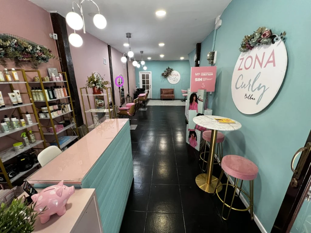 Interior del salón KizCurly, con recepción rosa y paredes turquesa